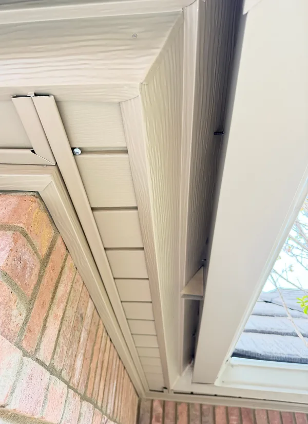 Looking up at a soffit and fascia corner from below, the wood under the roof edge