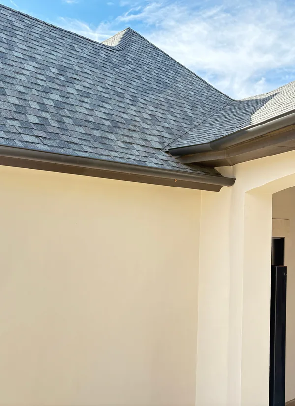 A dark gutter along the painted roof edge of a white stucco home