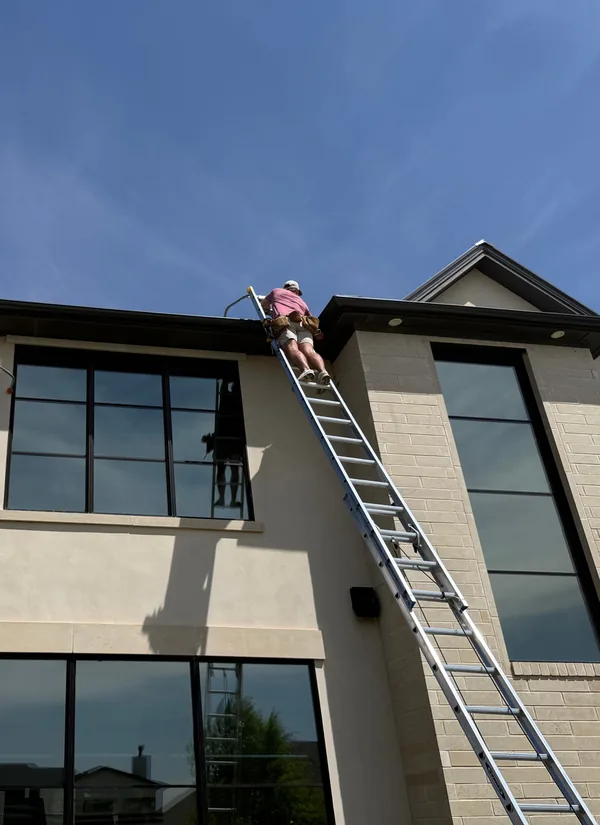 Two of our crew on tall ladders against a two-story stucco home.