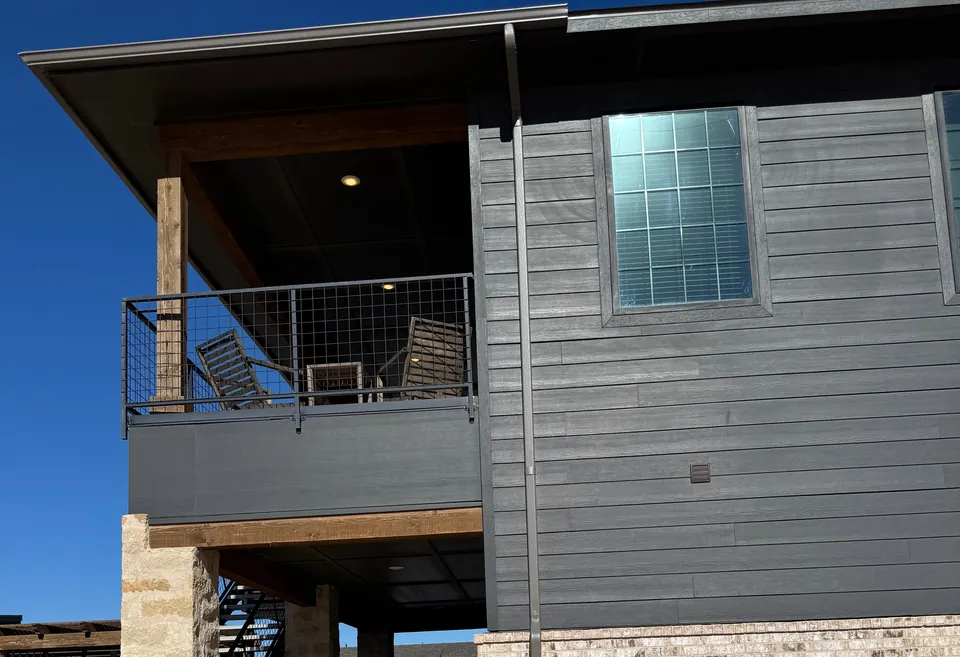 A two-story building with gray siding and a covered balcony.