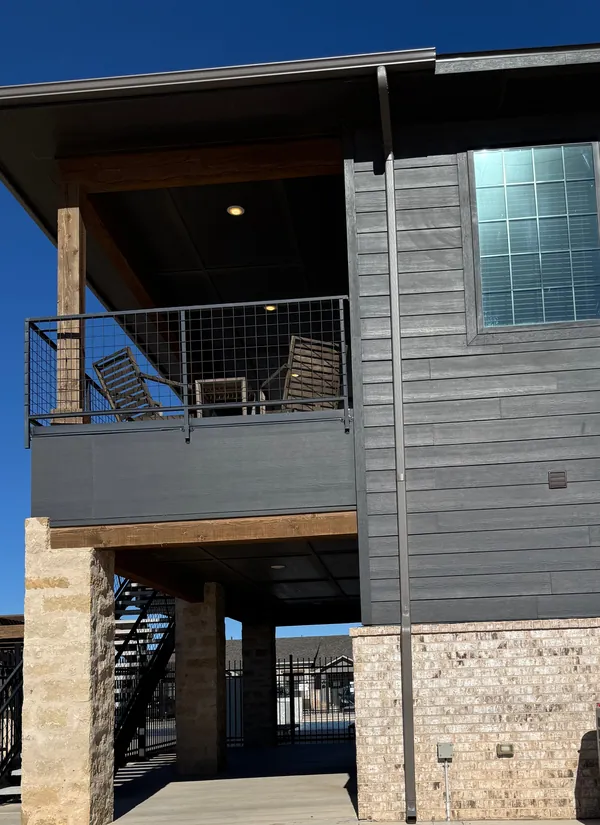 A two-story building with gray siding and a covered balcony.