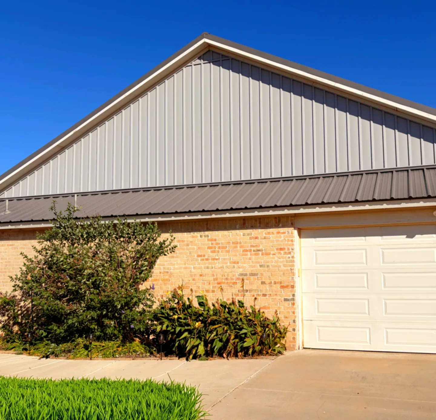 A garage gable in new metal siding under a deep blue sky