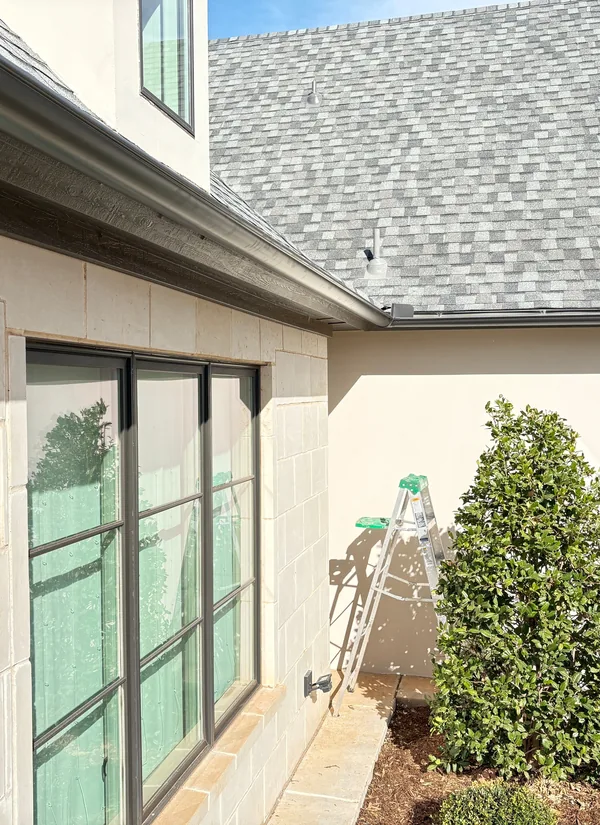 A row of black windows along a limestone wall under a dark gutter